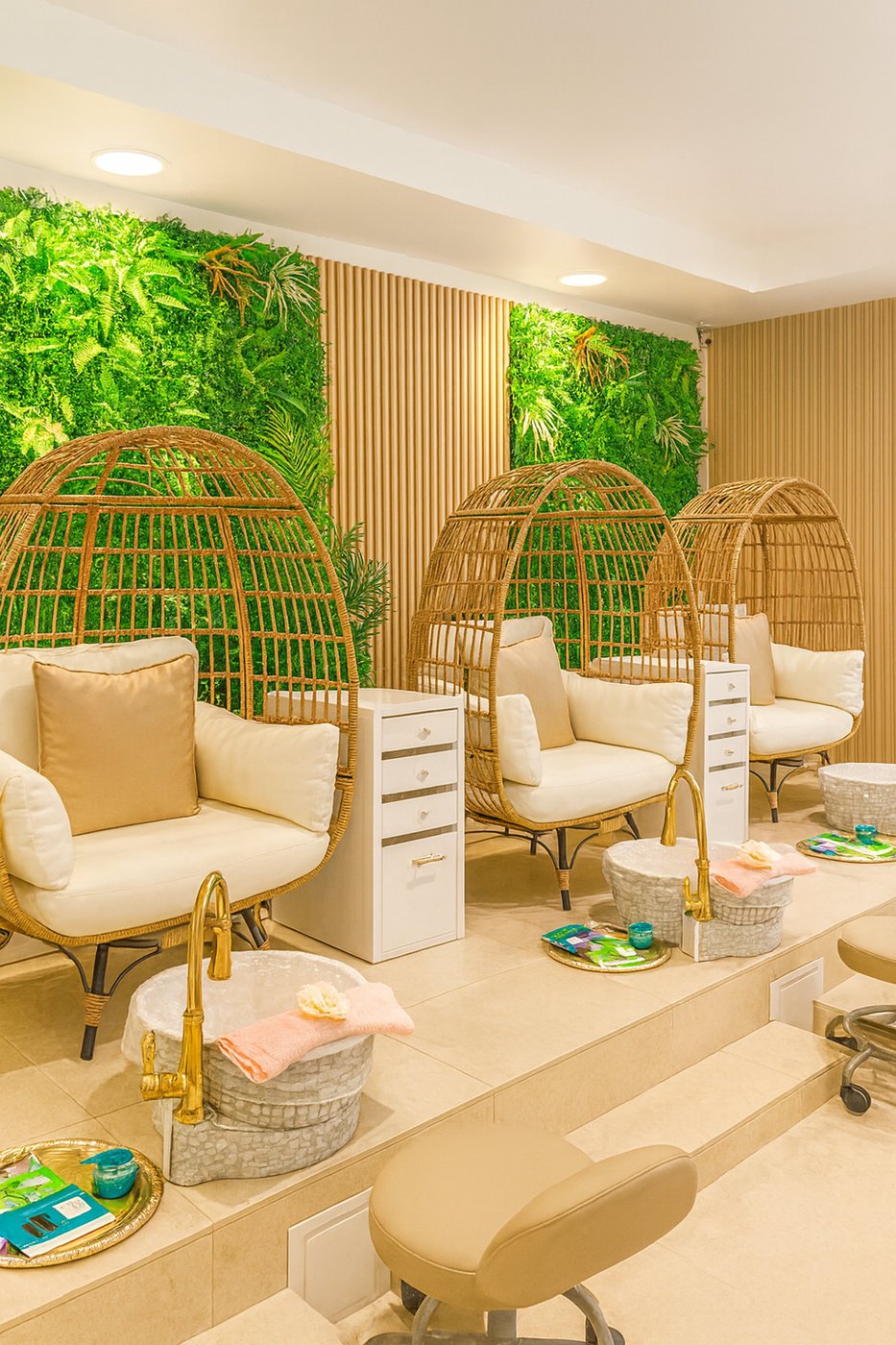 Majesty Day Spa luxury lounge: rattan egg chairs in front of a living green wall, with gold-finished foot basins